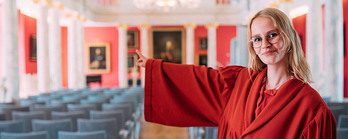 Kustodieführungen Ein Guide der Kustodie im roten Talar führt durch die Aula der Universität Greifswald.