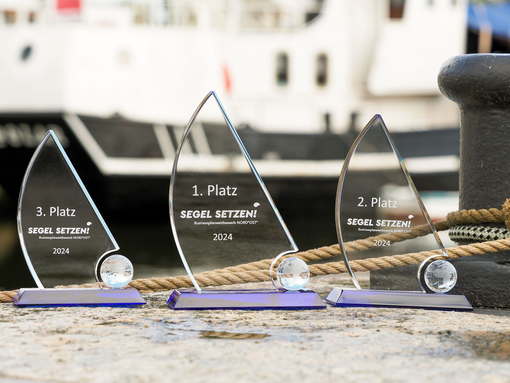 Pokale Businessplanwettbewerb Die Pokale wurden im Hafen fotografiert. Sie haben die Form von Segeln.