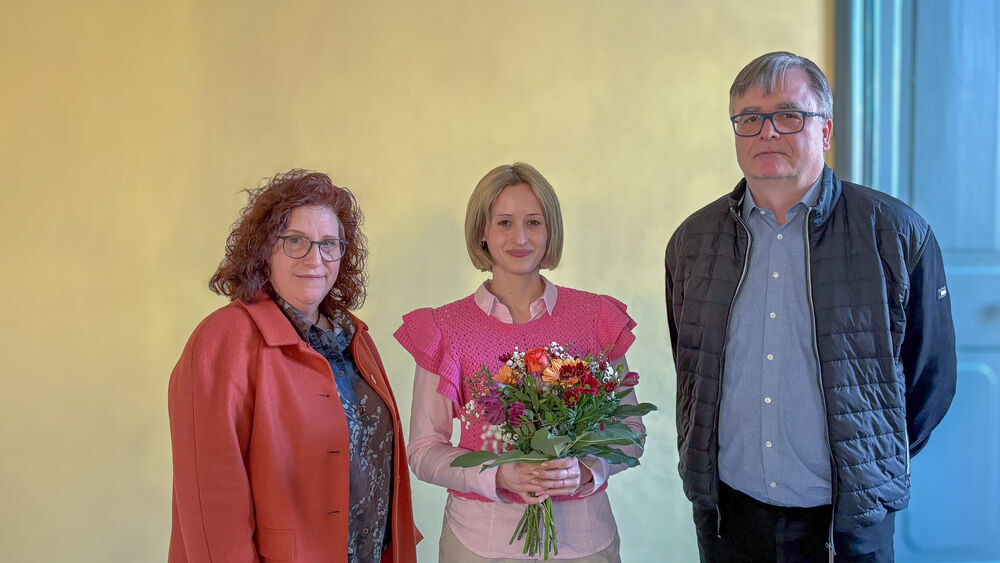 Wahl der studentischen Prorektorin Drei Personen stehen in einer Reihe, die in der Mitte hält einen Blumenstrauß