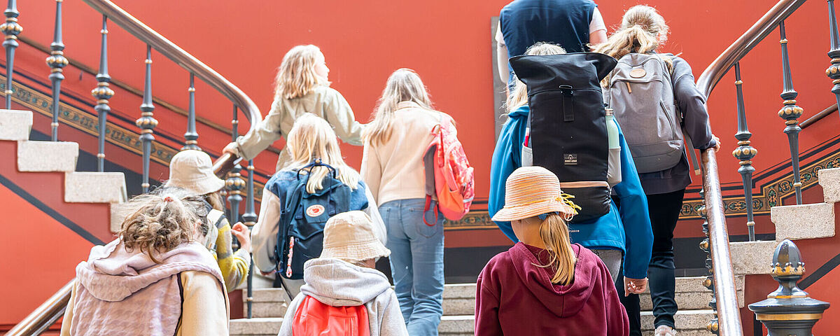 Kinder- und JugendUNI 2023 Während der Kinder- und JugendUNI 2023 gehen Kinder die große Treppe im Alten Audimax hinauf.