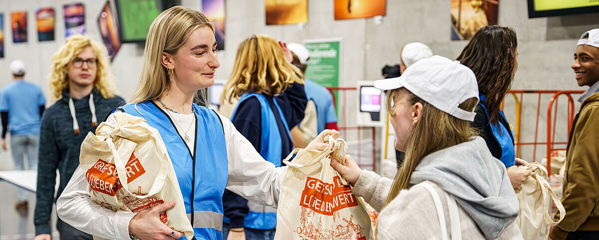 Freshers' welcome 2024 A student stands in the cafeteria with a bag and greets first-year students.