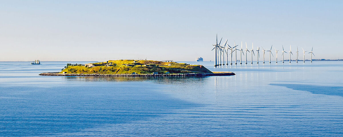 Symbolbild Ostseeforschung Eine Reihe Windräder steht hinter einer kleinen Insel in der Ostsee.