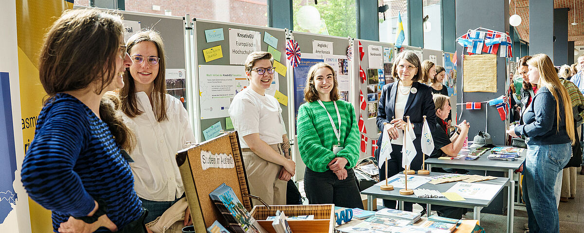 Symbolbild HIT 2025 Verschiedene Stände zu Auslandssemester, KreativEU und Studienfächer wie Anglistik/Amerikanistik sind zu sehen. Vor jedem Stsand stehen je 2 Repräsentant*innen, die im regen Austausch miteinander sind. Auf den Standtischen liegt Infomaterial.