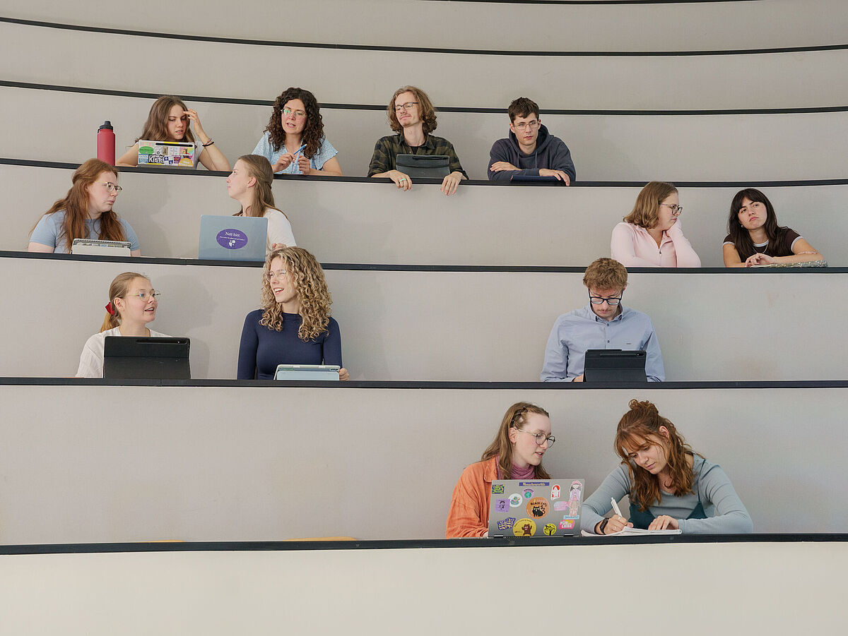 Imagefilm Grundschullehramt Studierende sitzen in einem Hörsaal und unterhalten sich.