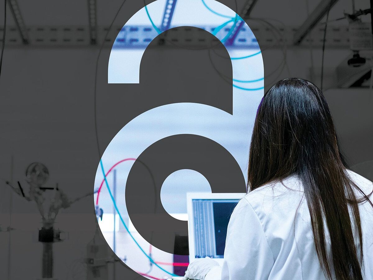 International Open Access Week 2026 Eine Frau mit schwarzen Haaren von hinten steht vor einem Glasfesnter mit einem großen A drauf.