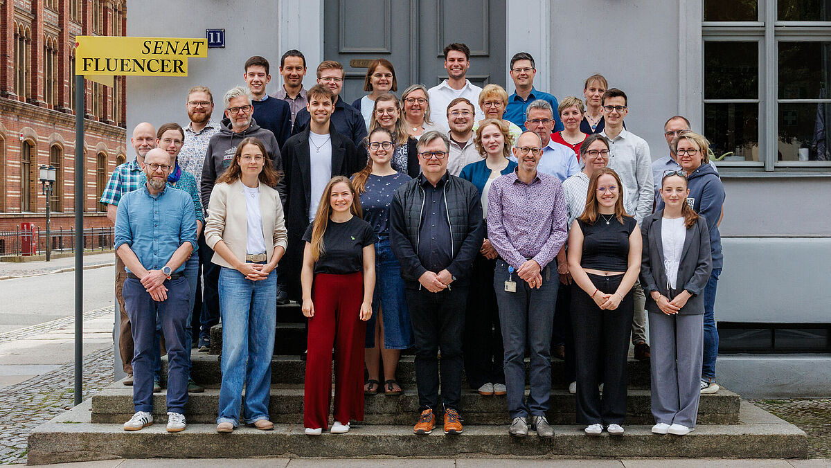 Gruppenfoto Senat 2026 (Senat Fluencer) Menschen stehen auf einer Treppe vor einem Haus