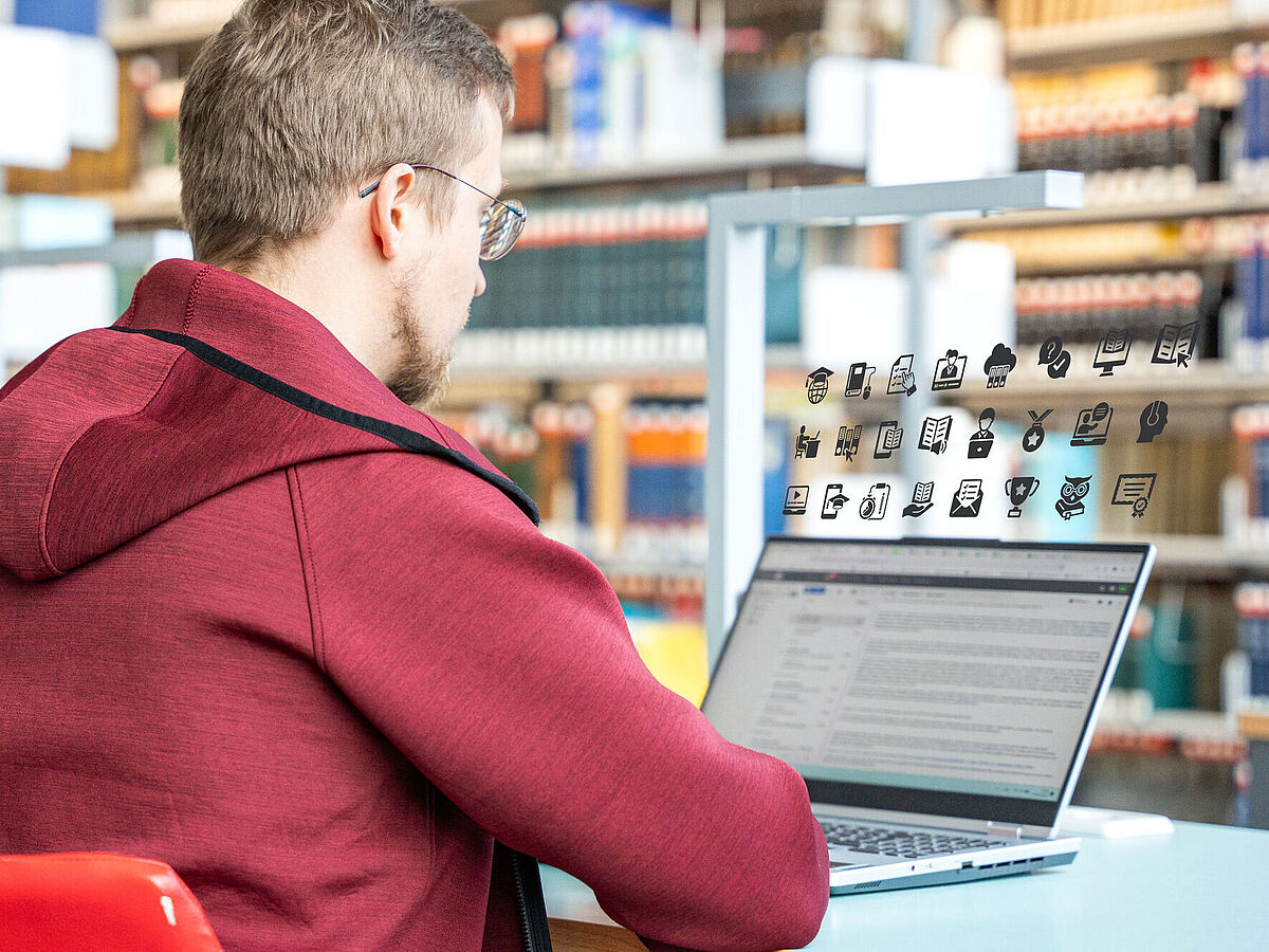 Symbolbild Digitalisierung in der Bibliothek In einer Bibliothek sitzt ein Student vor seinem Laptop.