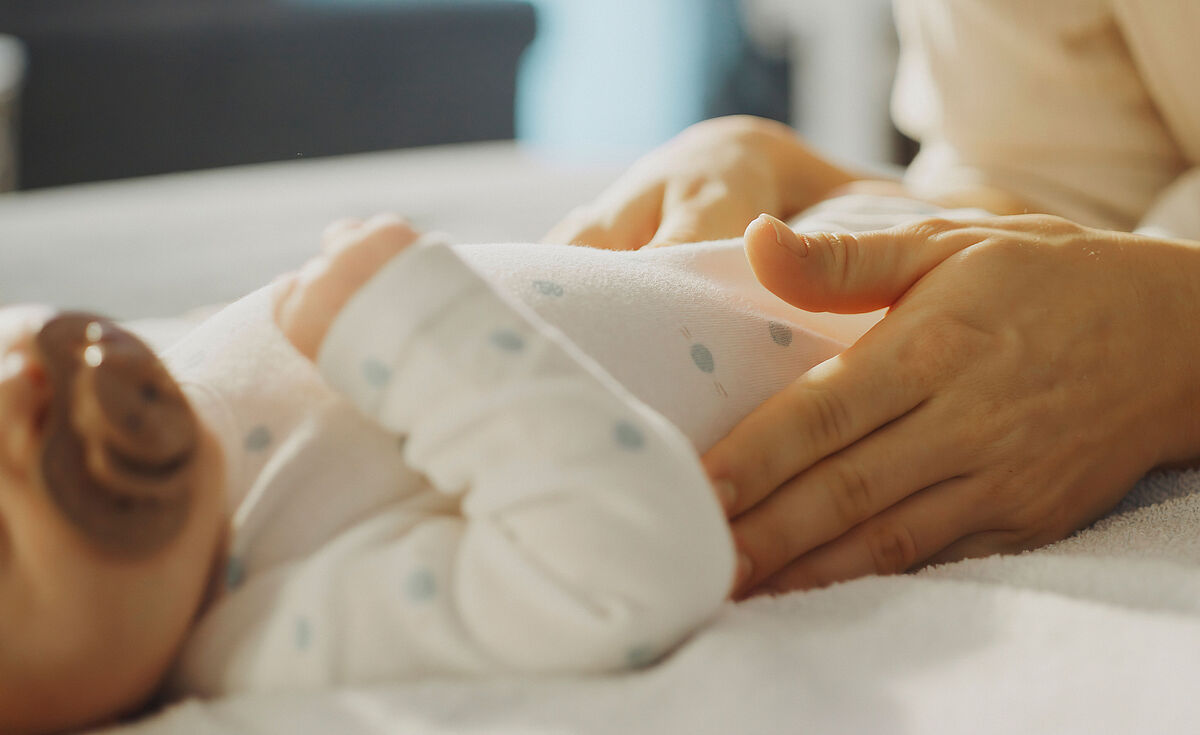 Symbolbild Mutter und Neugeborenes Auf einem Wickeltisch streichelt eine Mutter ihr kleines Baby.