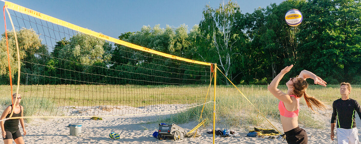 Beachvolleyball in Eldena Am Strand auf Sand stehen sich zwei Beachvolleyballspielerinnen gegenüber, während sich die rechte für den Aufschlag bereit macht.