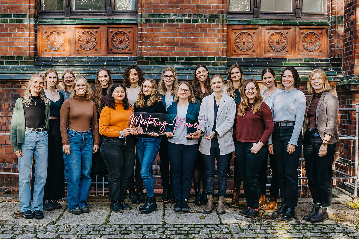 17 Frauen mit einem Schild "Mentoring-Moment"