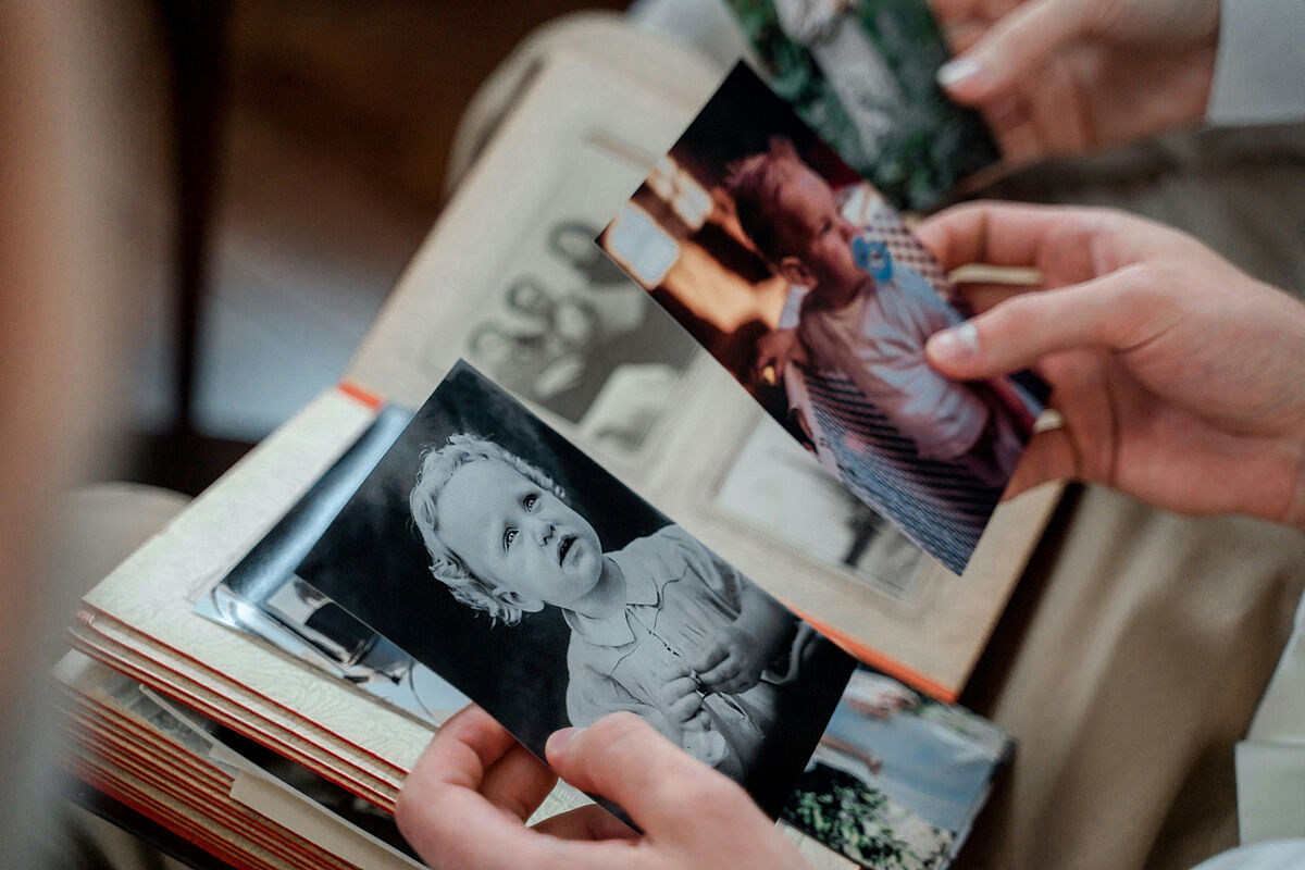 Stock photo of portrait photos from various generations Taking a look back at past experiences and adventures. Someone is flicking through a photo album.