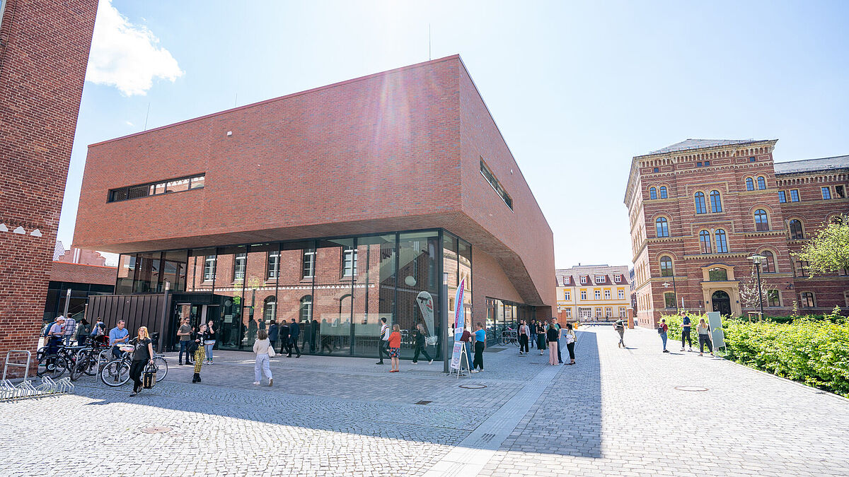 Neues Audimax Campus Loefflerstraße Viele Personen laufen um das Neue Audimax auf dem Campus Loefflerstraße. Zu sehen ist ebenfalls das neue Jura-Gebäude.