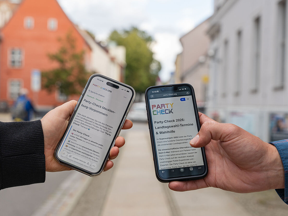 Onlinewahlhilfe 2026 Die Onlinewahlhilfe-App auf dem Smartphone. Zu sehen sind jeweils eine Hand zweier Personen, die Smartphones halten.