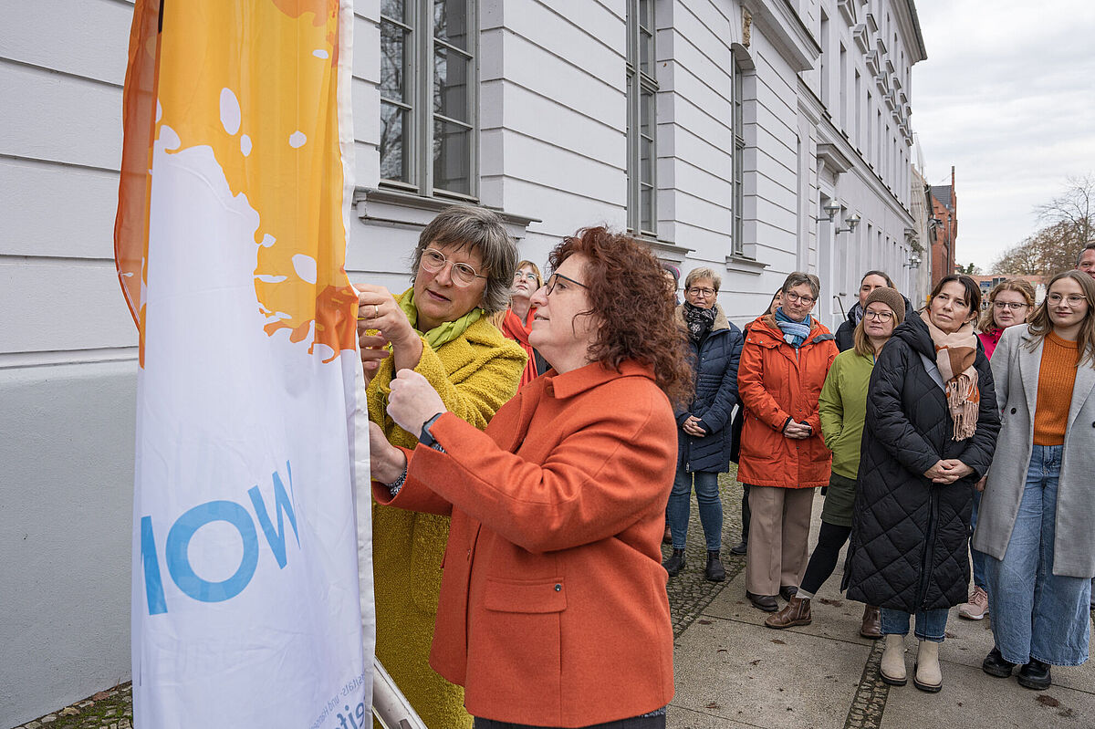 Die Gleichstellungsbeauftragte der Universität und die Rektorin hissen die UN-Woman-Fahne 2024