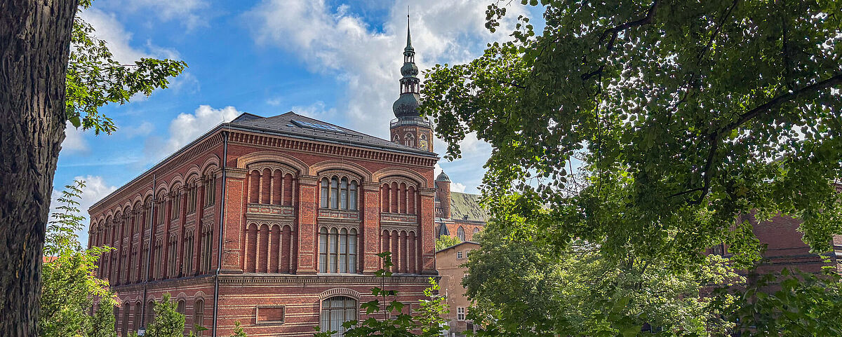 Alte Universitätsbibliothek Zwischen einem Rahmen aus grünen Blättern steht die rote, backsteinerne Alte Universitätsbibliothek.