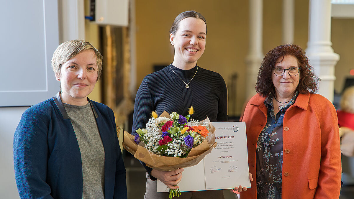 Vergabe des Genderpreises 2025 Auf dem Bild stehen drei Personen direkt vor der Kamera. (v.r.n.l.) Dr. Jenny Linek (Gleichstellungsbeauftragte), Isabell Sperke (Preisträgerin), Prof. Dr. Katharina Riedel (Rektorin)