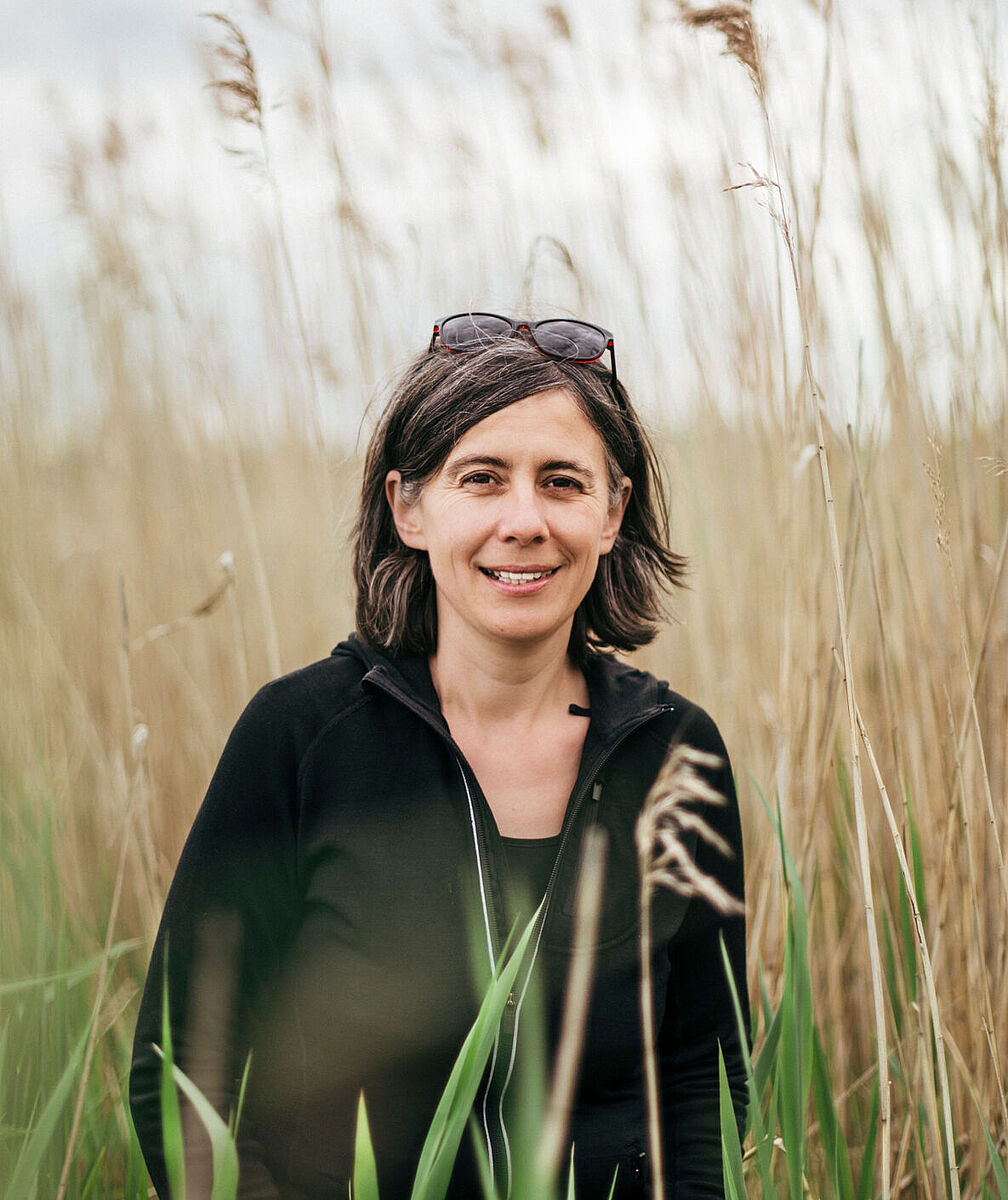 schwarzhaarige Frau vor Schilf