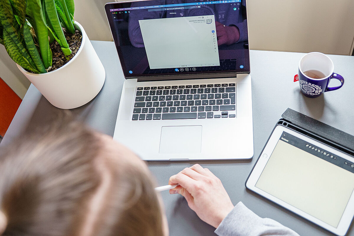 Symbolbild Online-Sitzung Eine Person sitzt vor einem geöffneten Laptop in einem Online-Meeting.