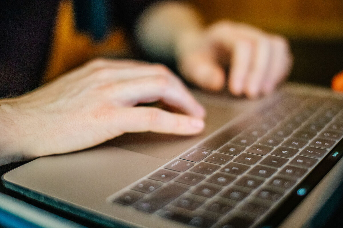Symbolbild Onlineumfrage Zu sehen sind die beiden Hände einer Person, die auf einer Tastatur tippen.