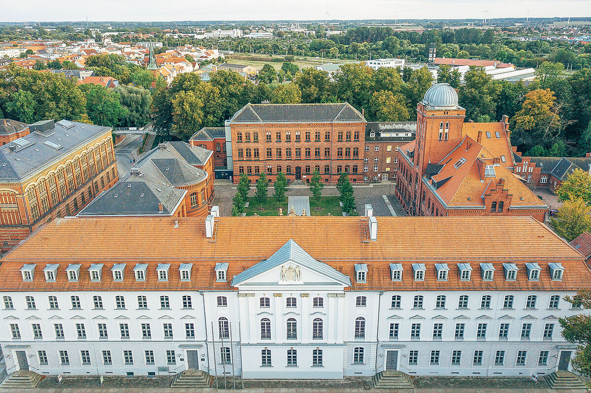 Historischer Campus Drohnenblick auf den Historischen Campus mit dem Unihauptgebäude im Vordergrund. Dahinter ist das Verwaltungsgebäude der Uni sichtbar. Links sieht man die Alte Unibibliothek sowie das Alte Audimax. Rechts ist die alte Physik mit der Sternwarte zu sehen. Im Hintergrund liegt der grüne Wall sowie weitere Stadtteile.